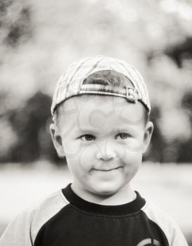 Happy Caucasian Child Boy Smiling Outdoors With Stripped Cap, Green Nature Background