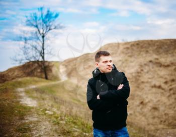 Young Handsome Man Stayed In Field, Meadow In Autumn Day. Casual Style - Jeans, Jacket