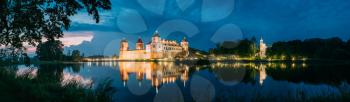 Mir, Belarus. Scenic Panoramic View Of Mir Castle Complex In Evening Illumination From Side Of Lake. Famous Landmark, Ancient Monument Under Blue Dramatic Sky.
