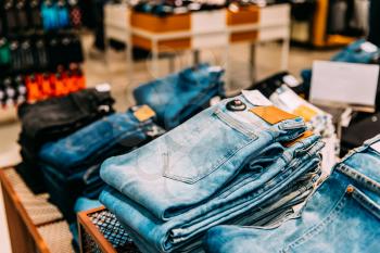 Stack Of Jeans On Shelves In Store Of Shopping Center.