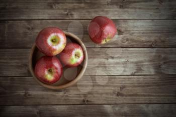 Red ripe apples in a saucer on the old wooden table