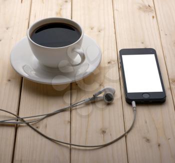 Smartphone headphones and a blank screen with a cup of coffee on your desktop