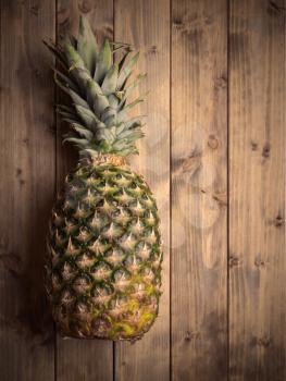whole pineapple on a wooden table. Photo in vintage style