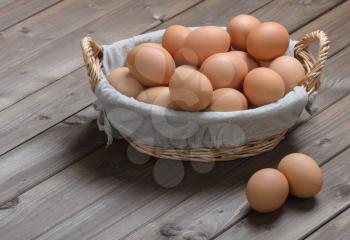 lot of chicken eggs in a basket on a wooden table