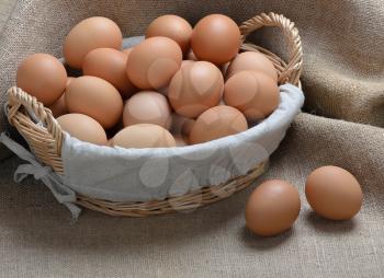 lot of chicken eggs in a basket on sackcloth background
