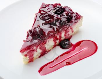 Slice of cheesecake with cherry jam on white plate  Closeup view
