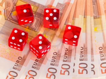 Red dice on top of some 50 euro banknotes