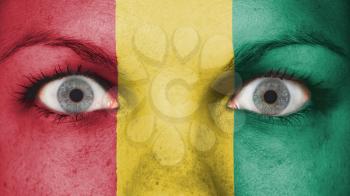 Close up of eyes. Painted face with flag of Guinea