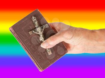 Old hand (woman) holding a very old bible, isolated on white, rainbow flag