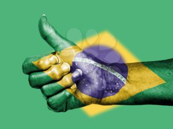 Old woman with arthritis giving the thumbs up sign, wrapped in flag pattern, Brazil