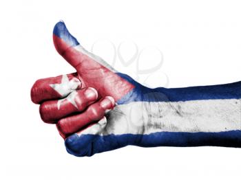 Old woman with arthritis giving the thumbs up sign, wrapped in flag pattern, Cuba