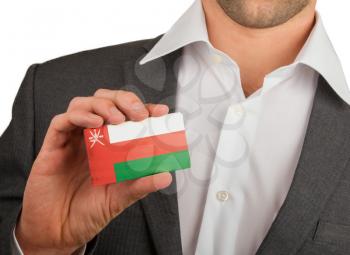 Businessman is holding a business card, flag of Oman