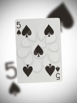 Playing card with a blurry background, five of spades