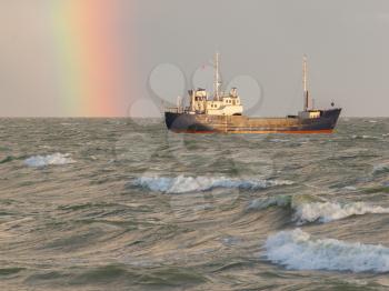 Small coastal vessel in the waters of the dutch Ijsselmeer, rainbow on the background