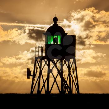 Silhouette of a green beacon at the dutch coast, sunset
