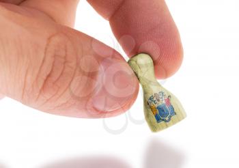 Hand holding wooden pawn with a flag painting, selective focus, New Jersey