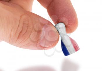 Hand holding wooden pawn with a flag painting, selective focus, France