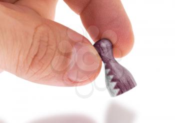 Hand holding wooden pawn with a flag painting, selective focus, Qatar