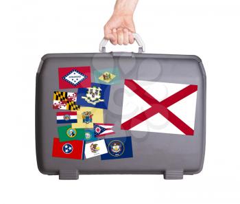 Used plastic suitcase with stains and scratches, stickers of US States, Alabama