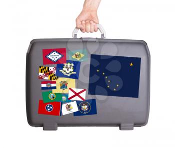 Used plastic suitcase with stains and scratches, stickers of US States, Alaska