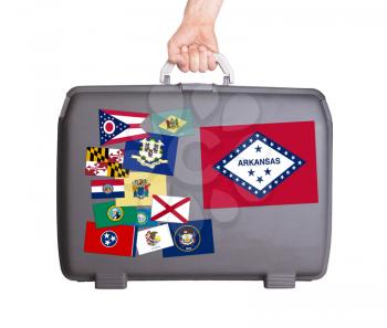 Used plastic suitcase with stains and scratches, stickers of US States, Arkansas