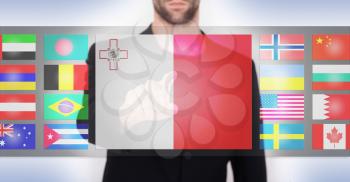 Hand pushing on a touch screen interface, choosing language or country, Malta
