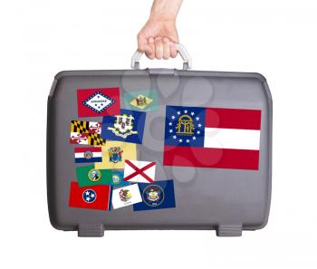 Used plastic suitcase with stains and scratches, stickers of US States, Georgia