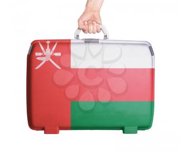 Used plastic suitcase with stains and scratches, printed with flag, Oman