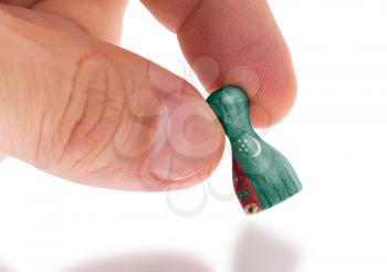 Hand holding wooden pawn with a flag painting, selective focus, Turkmenistan
