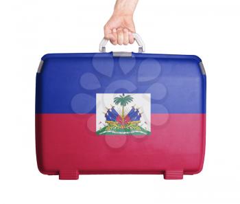 Used plastic suitcase with stains and scratches, printed with flag, Haiti