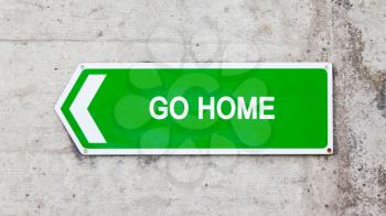 Green sign on a concrete wall - Go home