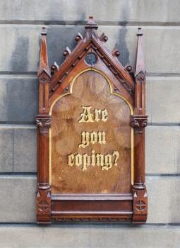 Decorative wooden sign hanging on a concrete wall - Are you coping