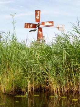 Small and rusted old metal windmill at the waterside, Netherlands