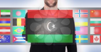 Hand pushing on a touch screen interface, choosing language or country, Libya