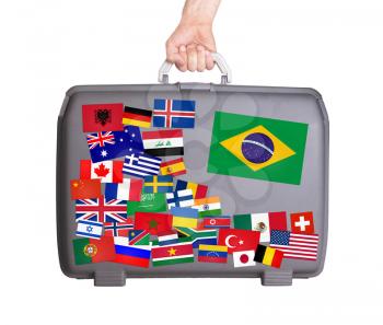 Used plastic suitcase with lots of small stickers, large sticker of Brazil