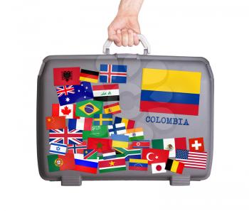 Used plastic suitcase with lots of small stickers, large sticker of Colombia