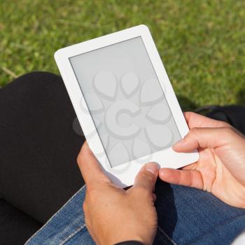 Woman reading ebook on the grass, square image