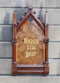 Decorative wooden sign hanging on a concrete wall - Happy new year