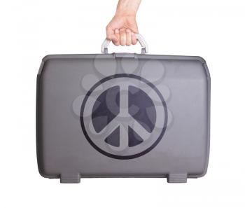 Used plastic suitcase with stains and scratches, printed with sign, peace
