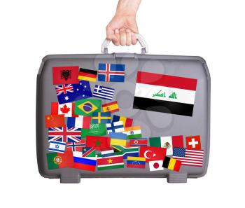 Used plastic suitcase with lots of small stickers, large sticker of Iraq