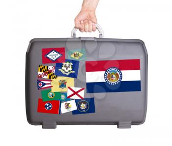 Used plastic suitcase with stains and scratches, stickers of US States, Missouri