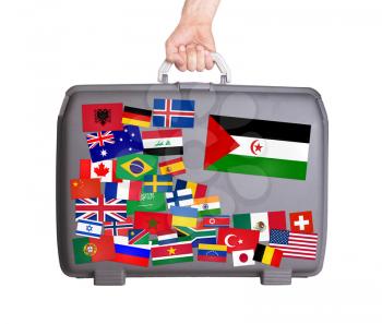 Used plastic suitcase with lots of small stickers, large sticker of Western Sahara