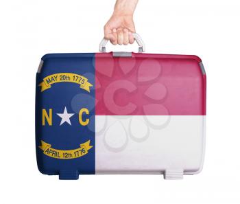 Used plastic suitcase with stains and scratches, printed with flag, North Carolina