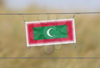 Border fence - Old plastic sign with a flag - Maldives