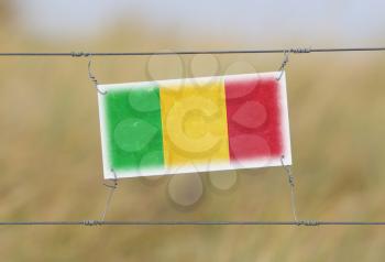 Border fence - Old plastic sign with a flag - Mali
