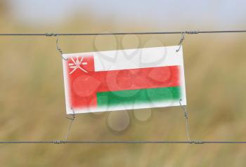Border fence - Old plastic sign with a flag - Oman