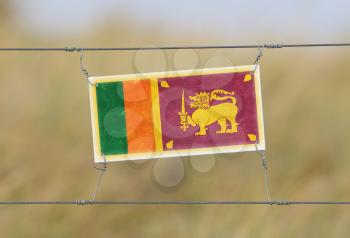 Border fence - Old plastic sign with a flag - Sri Lanka