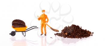 Miniature worker with broom working on a grinded coffee bean