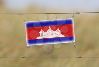 Border fence - Old plastic sign with a flag - Cambodia