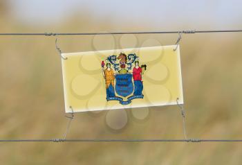 Border fence - Old plastic sign with a flag - New Jersey